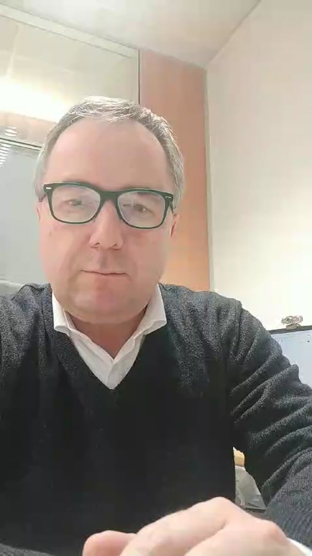 Fermo immagine del video: un uomo con gli occhiali e il maglione scuro parla alla fotocamera dallo studio.